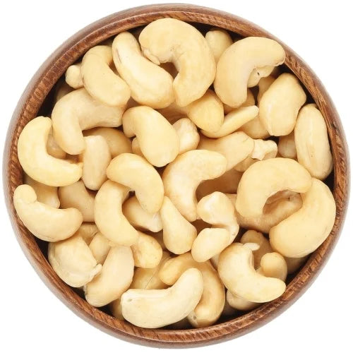 Raw cashew nuts piled in a round wooden bowl against a plain white background.