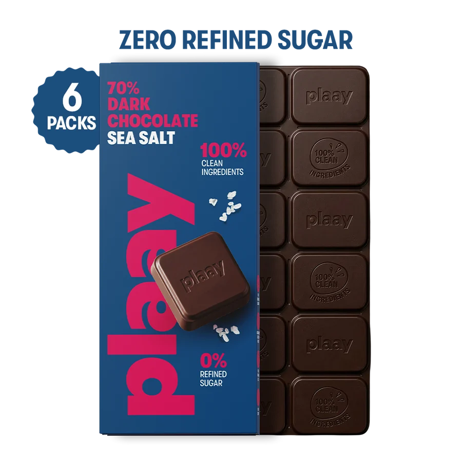 A package of Plaay zero refined sugar chocolate sea salt bars, showing a blue 6-pack box next to a bar of dark chocolate squares. The packaging features bold pink and white text, and the chocolate bars are embossed with the Plaay logo.