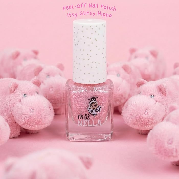 Pink nail polish bottle with plush hippo toys on a pink background