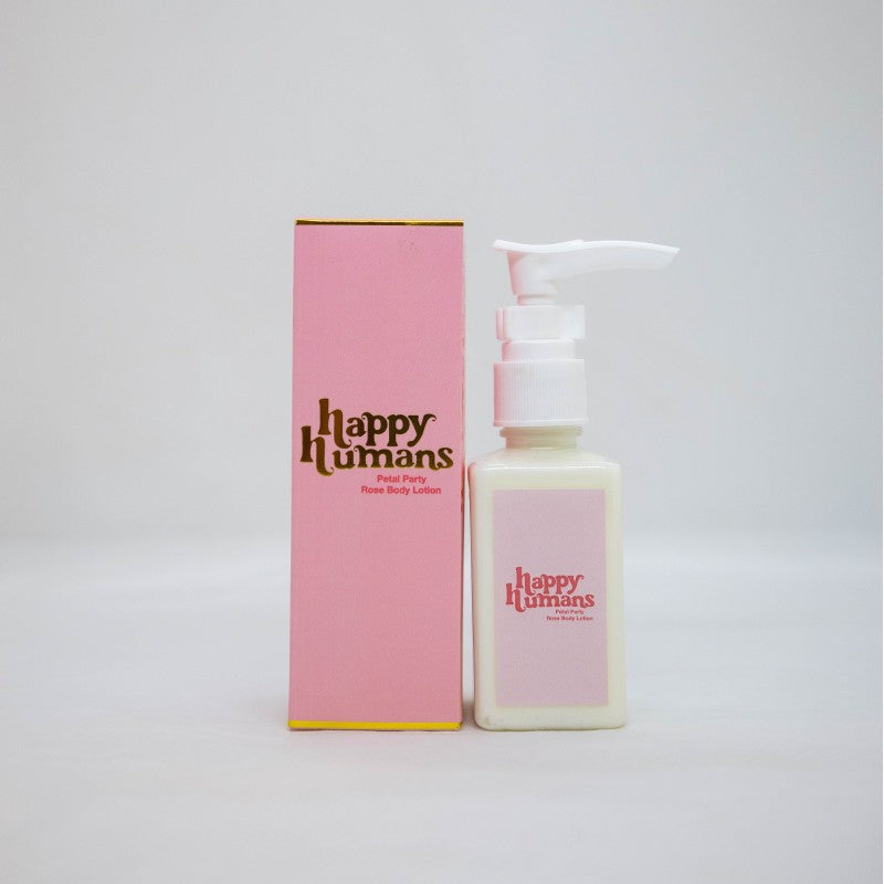 A bottle of Happy Humans Facial Cream next to its pink packaging box, set against a plain light gray background.