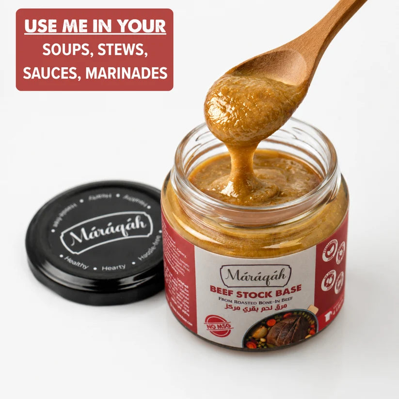 A jar of Miráqah Beef Stock Base with its black lid placed beside it on a white background. A wooden spoon is lifting a glossy, thick brownish-orange paste from the open jar.