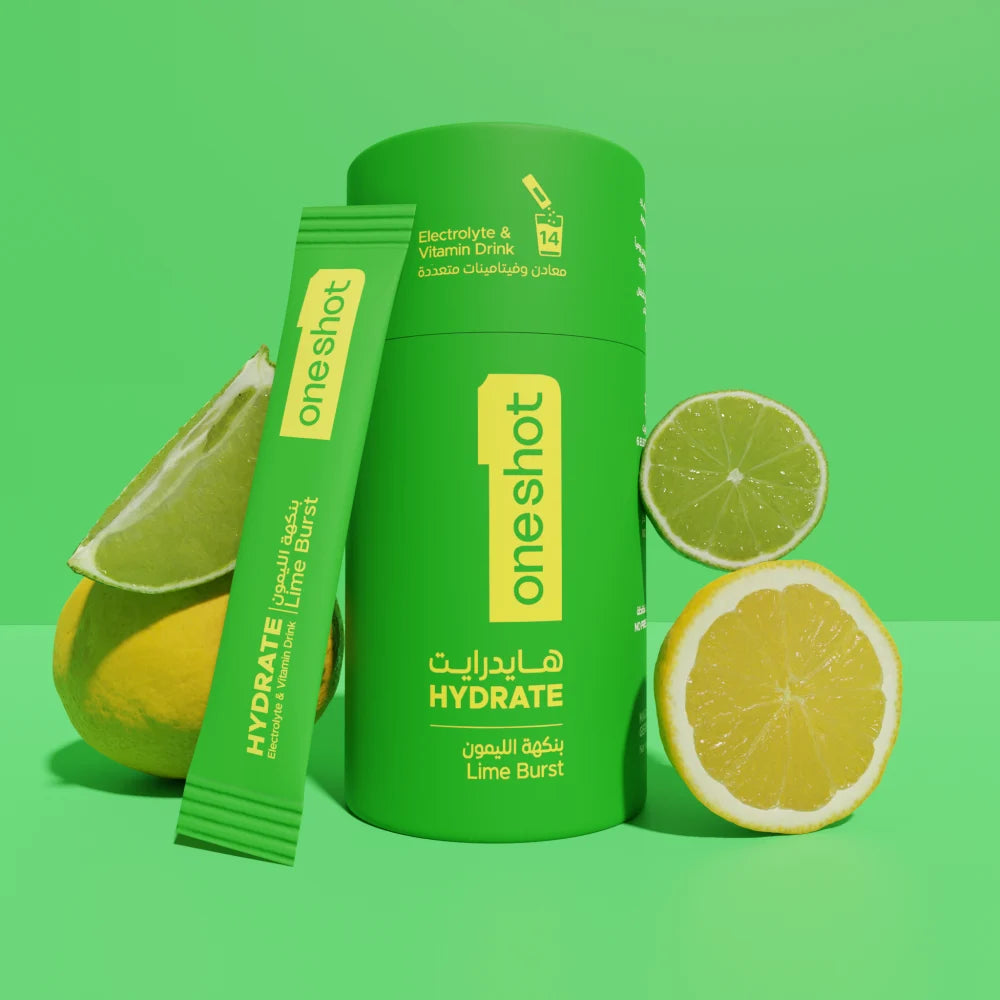 A green cylindrical bottle and a matching single-serve packet from the brand one shot, labeled HYDRATE Lime Burst, styled with sliced lemons and limes on a bright green background.