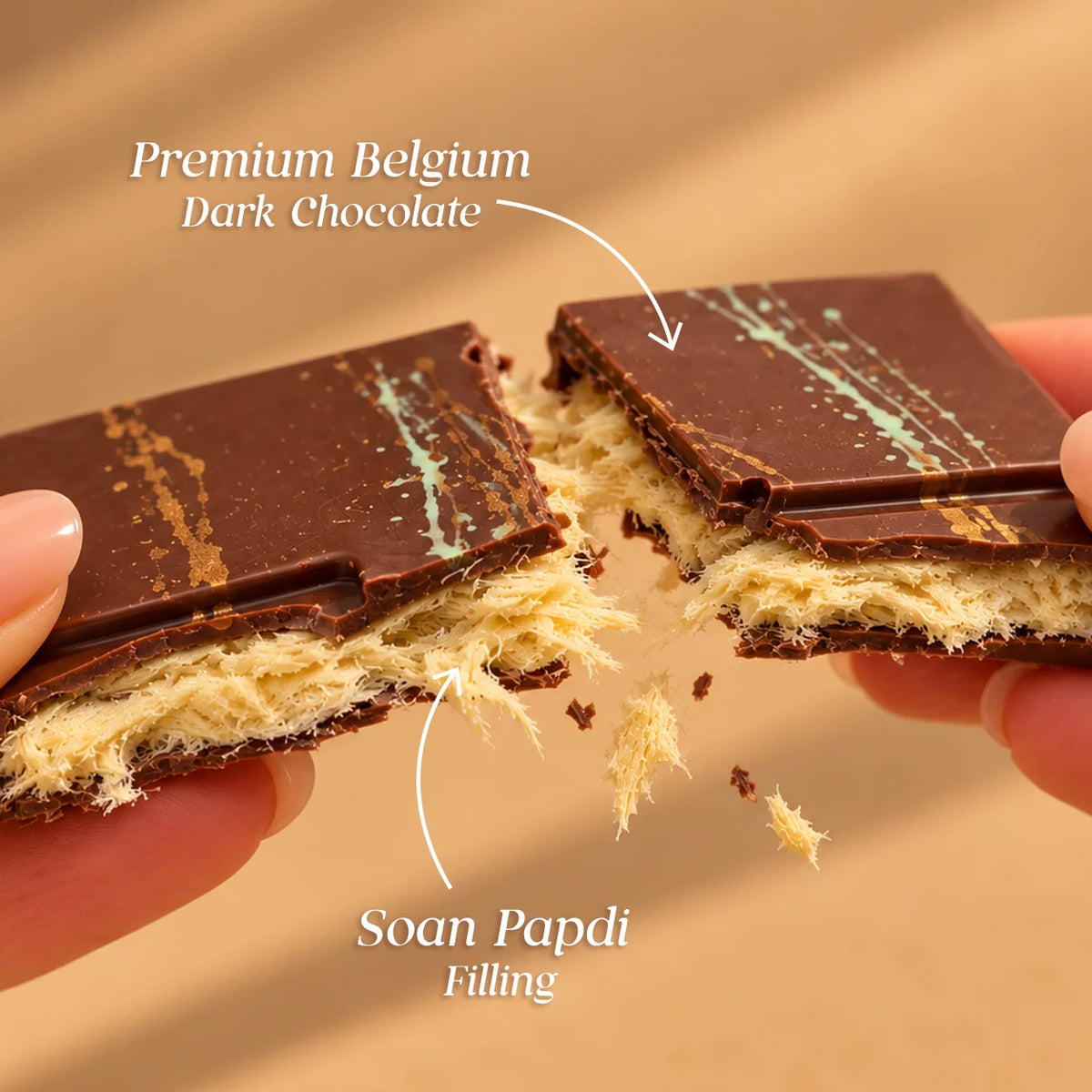 A close-up of a chocolate wafer bar being held and split by two hands, with text labels reading 'Premium Belgium Dark Chocolate' and 'Soan Papdi Filling.'.