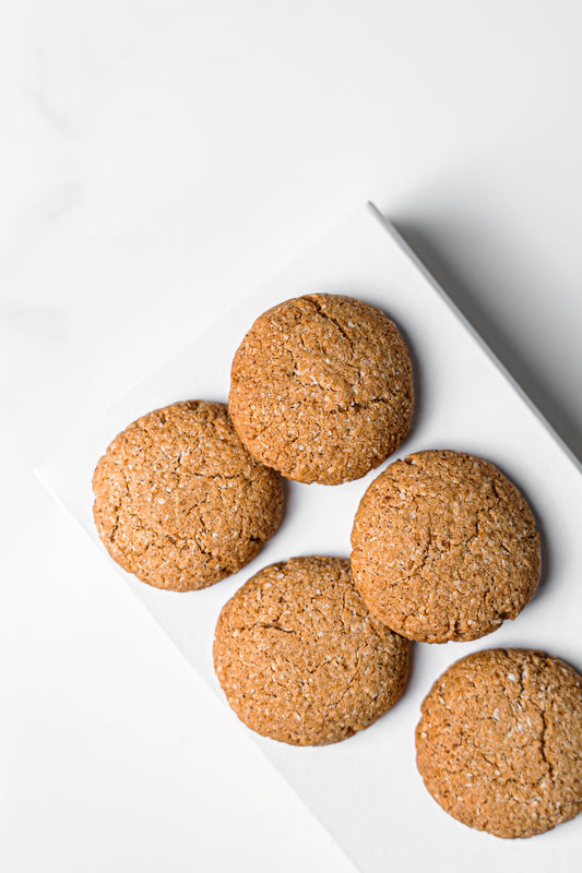 Five golden-brown gingerbread cookies arranged on a white rectangular plate against a clean white background.