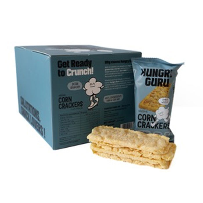 A box of Hungry Guru Corn Crackers alongside a single bag of the crackers and a stack of two square corn crackers in front, on a plain white background.