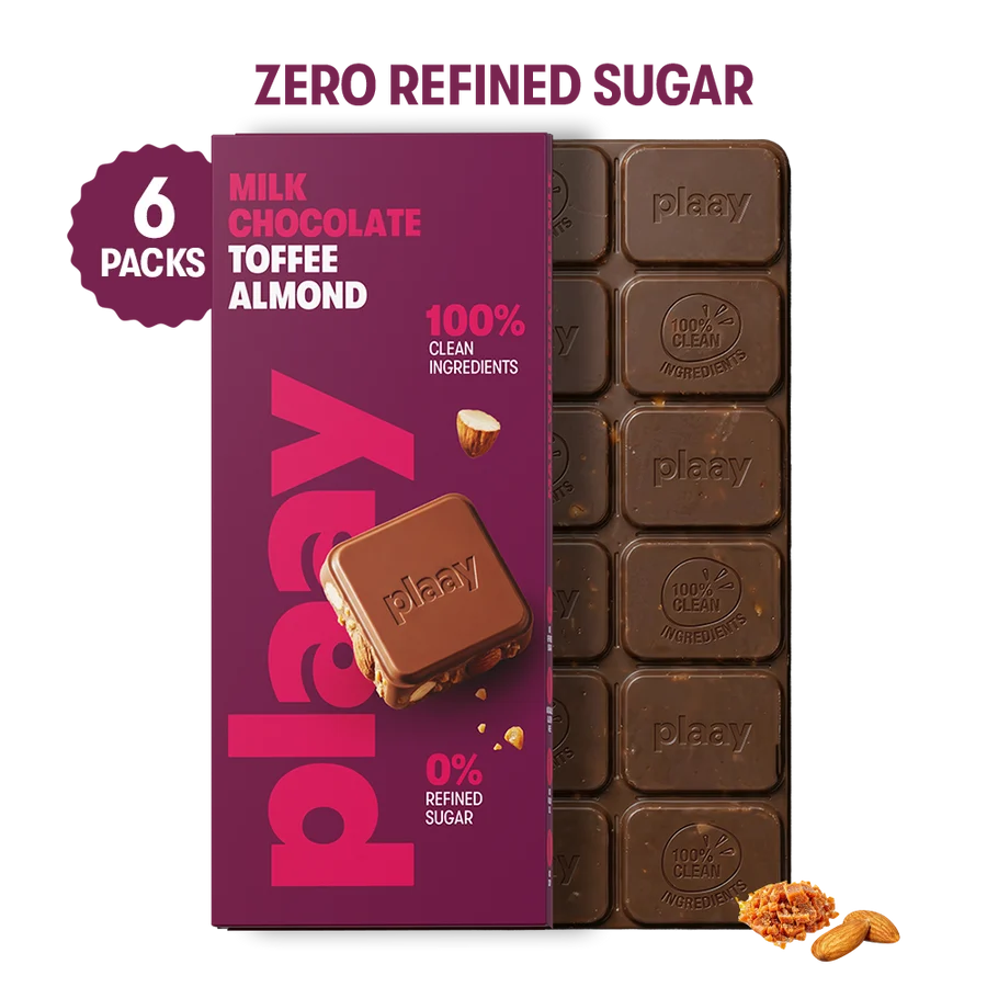 A boxed pack of Plaay milk chocolate toffee almond bars shown on a white background, with a purple front label, a dark chocolate bar partially visible behind it, and a '6 PACKS' badge. Text at the top reads 'ZERO REFINED SUGAR'.