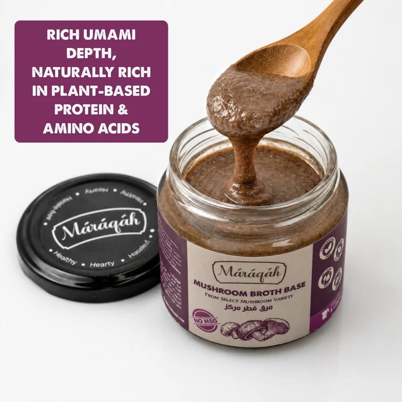 A jar of Maraqah Mushroom Broth Base with its lid off, showing a wooden spoon lifting the thick brown broth. A purple text overlay on the left highlights the product's umami depth and plant-based protein and amino acid content.