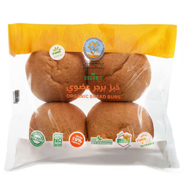 A package of four organic bread buns in a clear plastic bag with a yellow top flap. The buns are golden brown, and the packaging features several certification logos and text including 'ORGANIC BREAD BUNS' and '100% FRESH'.