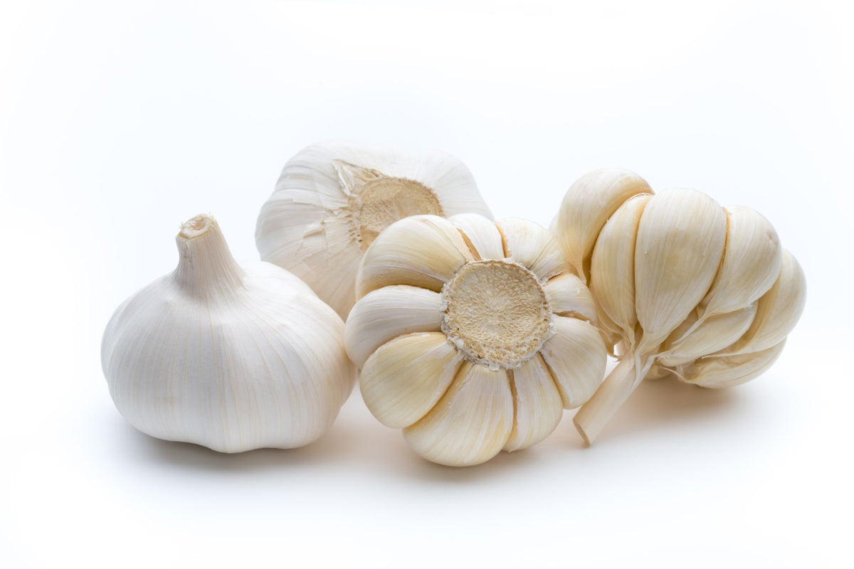 Three whole heads of garlic with pale ivory to off-white papery skins, arranged on a clean white background.