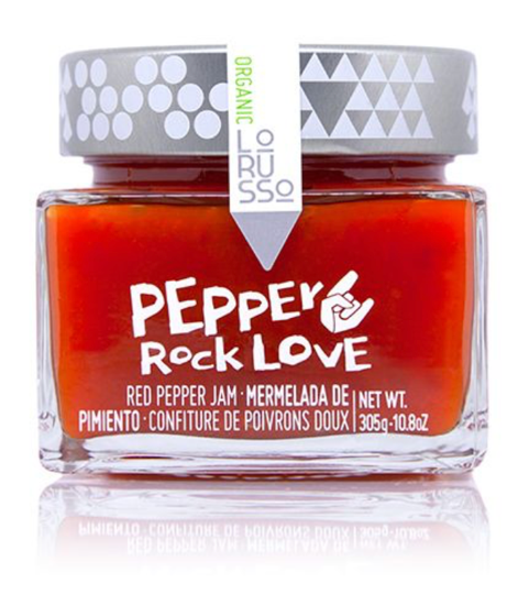 A jar of Lo RuSSO Pepper Rock Love red pepper jam, featuring a vibrant red-orange jam inside a clear glass jar with a gray patterned lid and a white paper label.