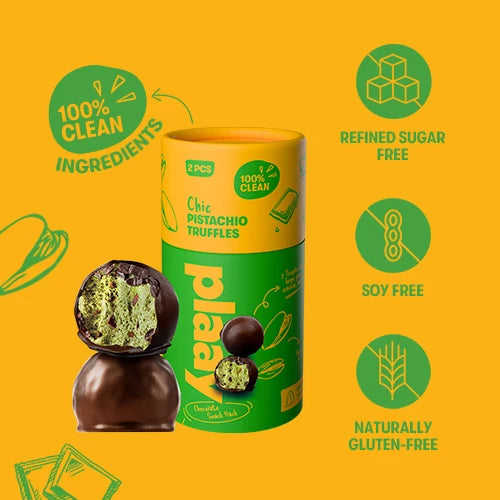 A cylindrical tin of Plaay Chic Pistachio Truffles on a bright yellow background, with one truffle shown broken open in front. Green and yellow packaging features include claims like 100% clean ingredients, refined sugar free, soy free, and naturally gluten free.