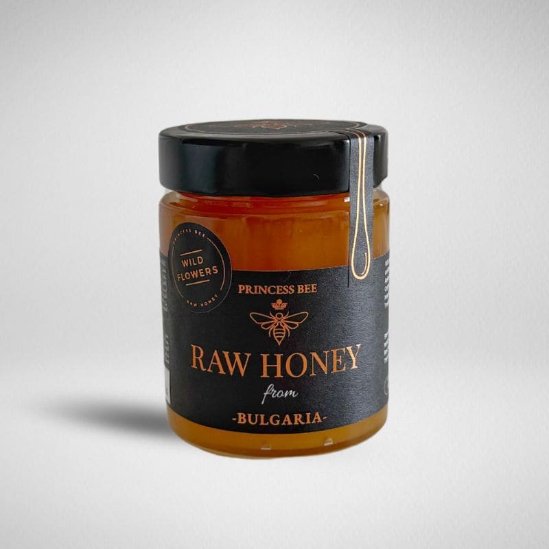 A glass jar of Princess Bee Raw Honey from Bulgaria, featuring amber-colored honey inside and a black label with gold lettering, sealed with a black lid and a wax seal.