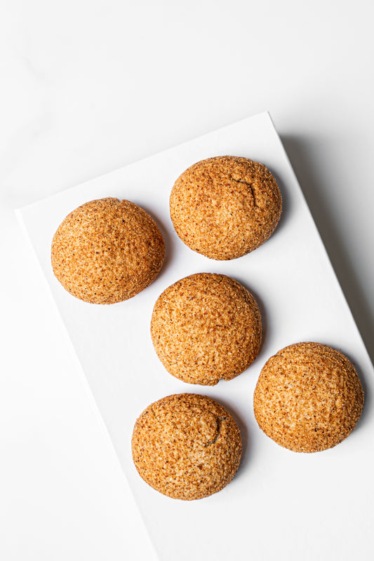 Five golden-brown sugar cookies arranged on a white rectangular plate against a clean white background.