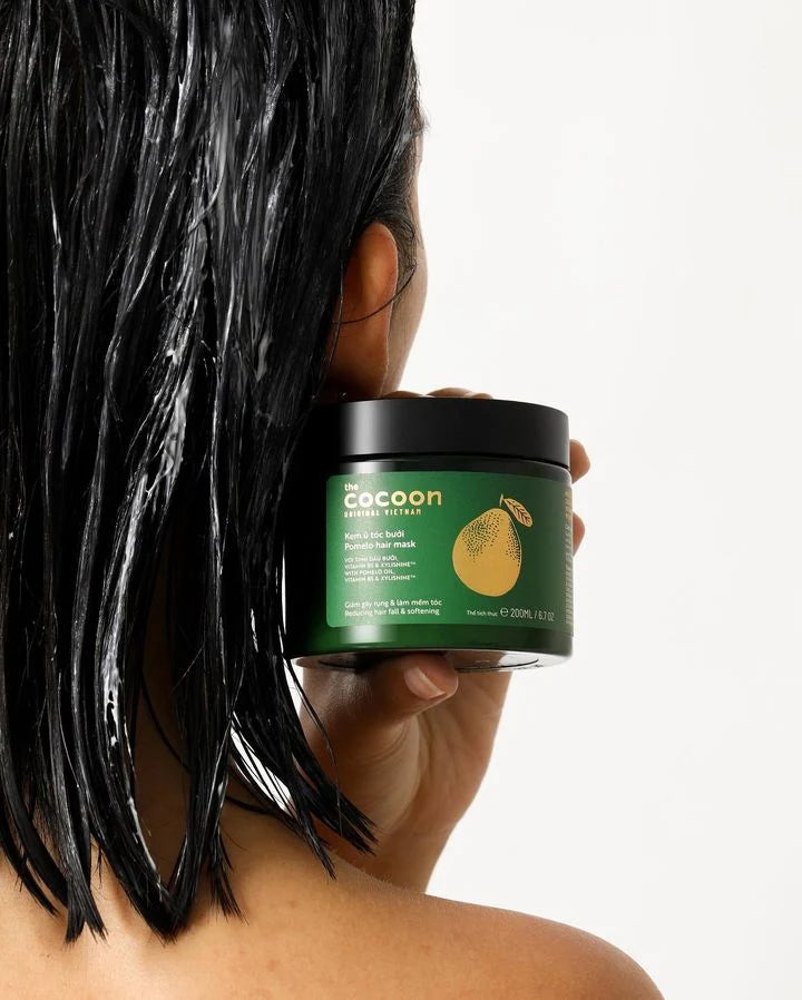 Person holding a jar of Cocoon hair product with wet hair