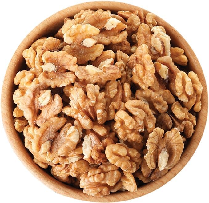 A top-down view of raw, shelled walnuts piled in a round wooden bowl against a solid white background.