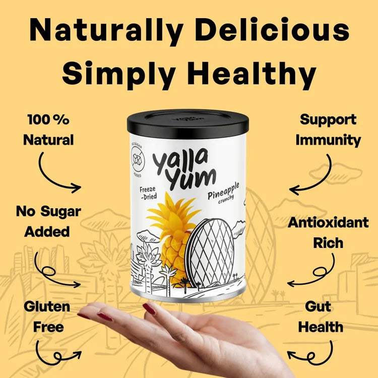 A hand holding a cylindrical canister of Yalla Yum Pineapple Creamery against a yellow graphic background with text highlighting product benefits like 100% natural, no sugar added, gluten free, antioxidant rich, and support immunity.
