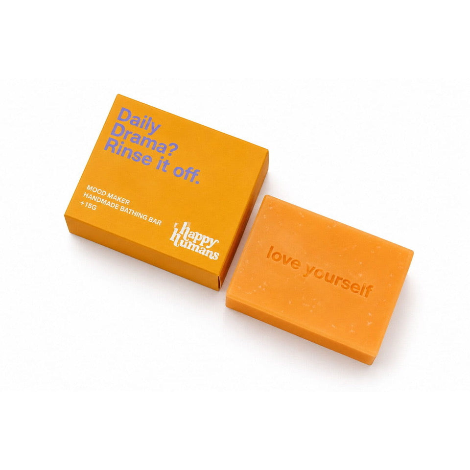 An orange wooden handmade bath bar next to its matching orange packaging box on a clean white background. The bar is embossed with the words 'love yourself' and the box features blue text reading 'Daily Cramax? Riser K off' and the Happy Kitchens logo.