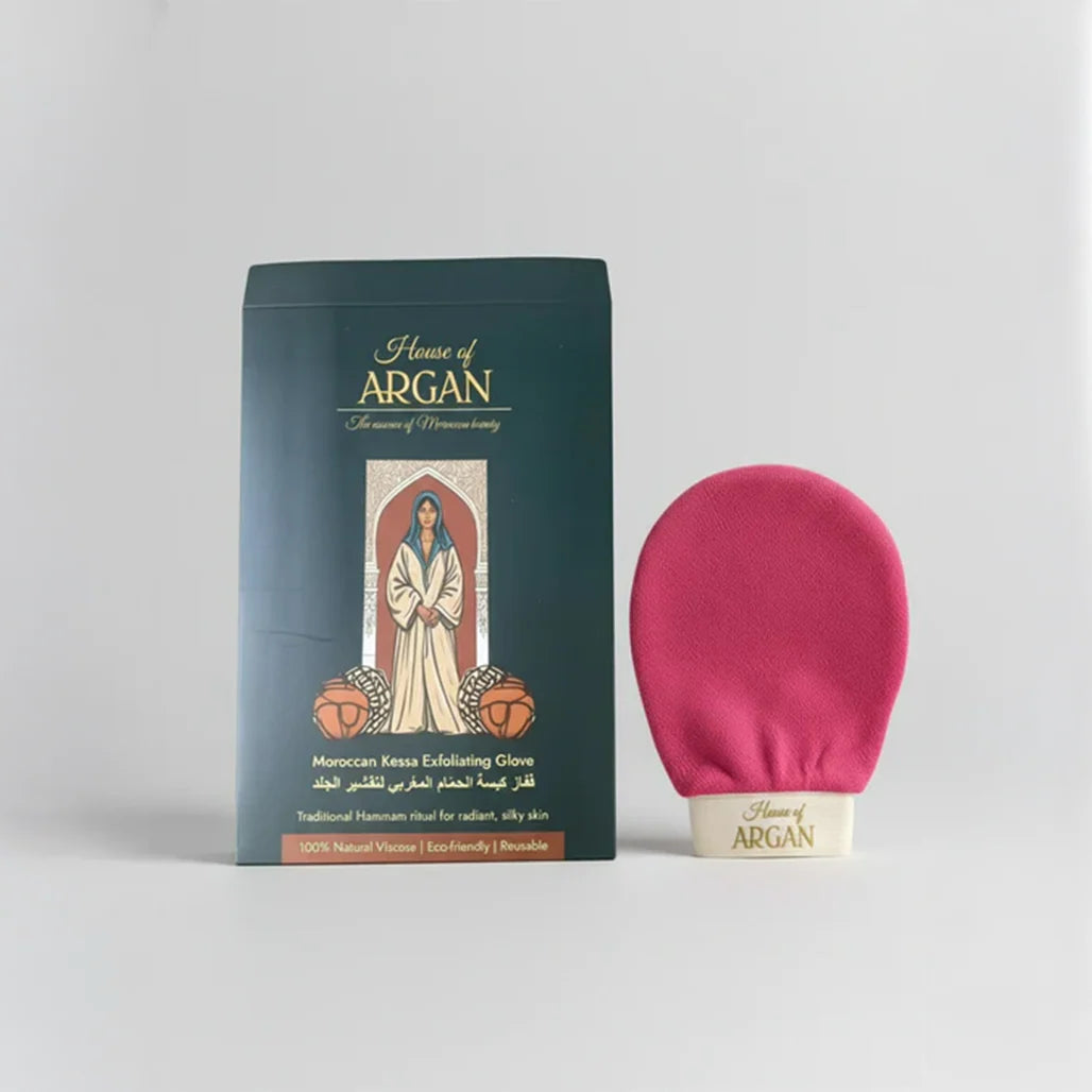 A dark teal box labeled 'House of ARGAN Moroccan Kessa Exfoliating Cream' stands next to a bright pink circular exfoliating glove on a light gray background.