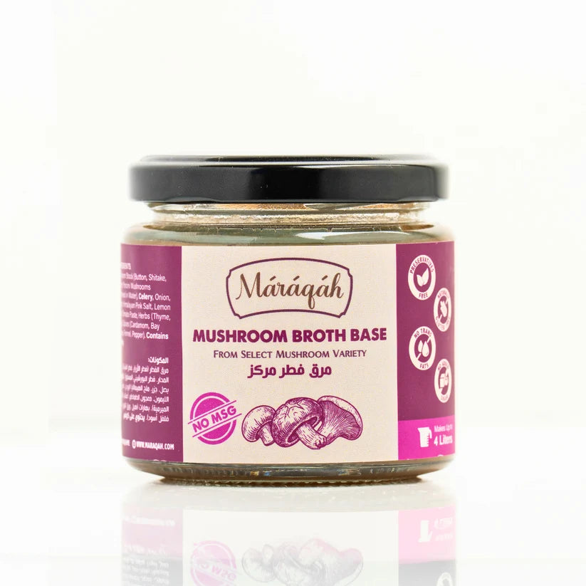A glass jar of Maraqah Mushroom Broth Base with a black lid and a pink and white label, set against a clean white background with a soft reflection below.