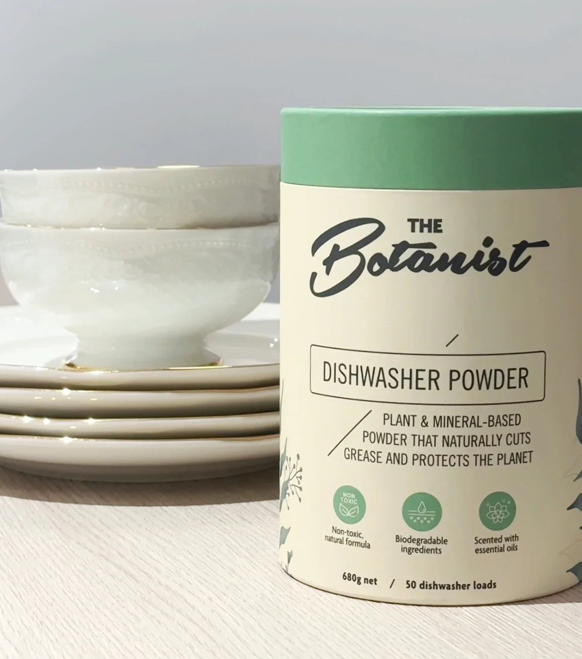Dishwasher powder container labeled 'The Botanist' with bowls in the background