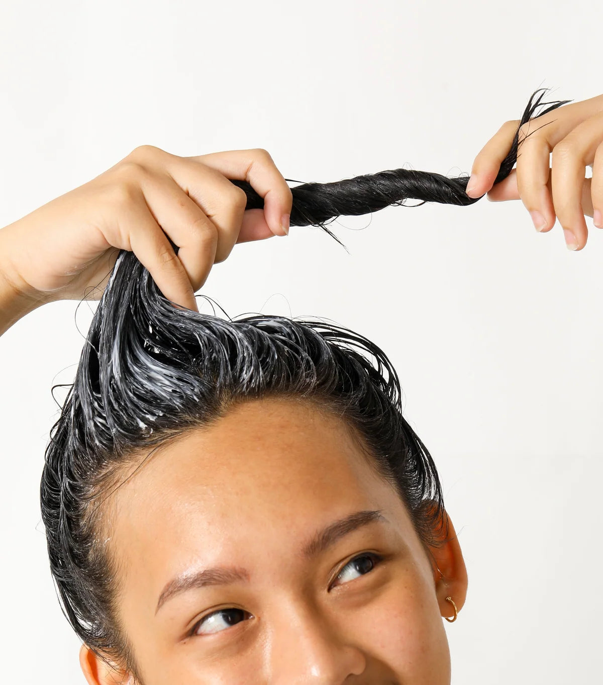 Person with black hair being styled against a white background